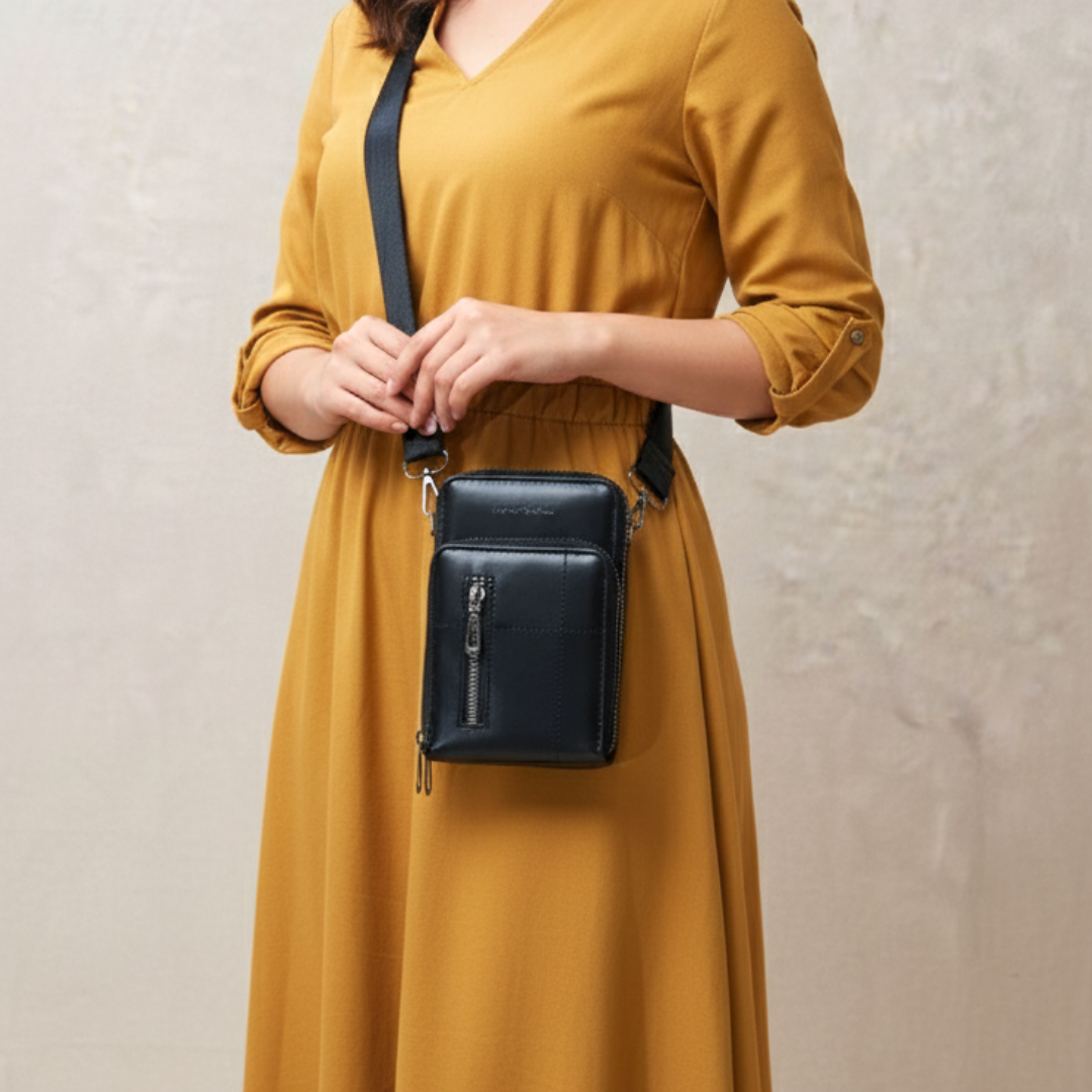 Person wearing a mustard yellow dress holding a black crossbody bag against a neutral background