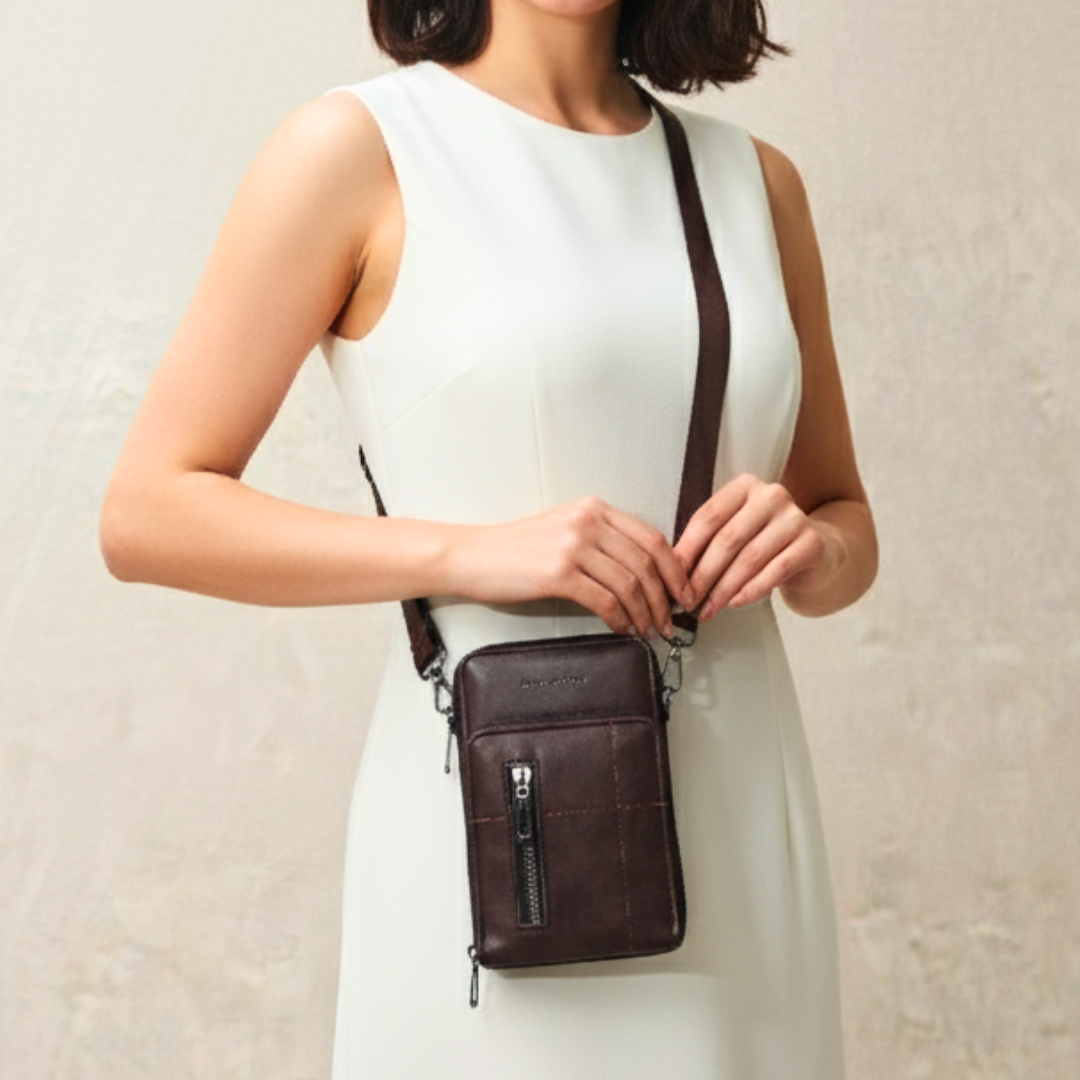 Woman wearing a brown leather crossbody bag against a plain background