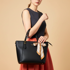 Woman holding a black handbag with a decorative ribbon against a beige background