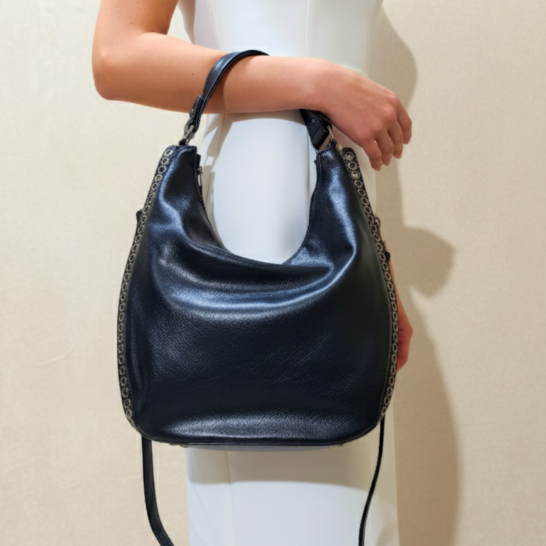Black handbag held by a person against a plain background