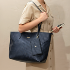 Person holding a navy blue textured handbag against a neutral background
