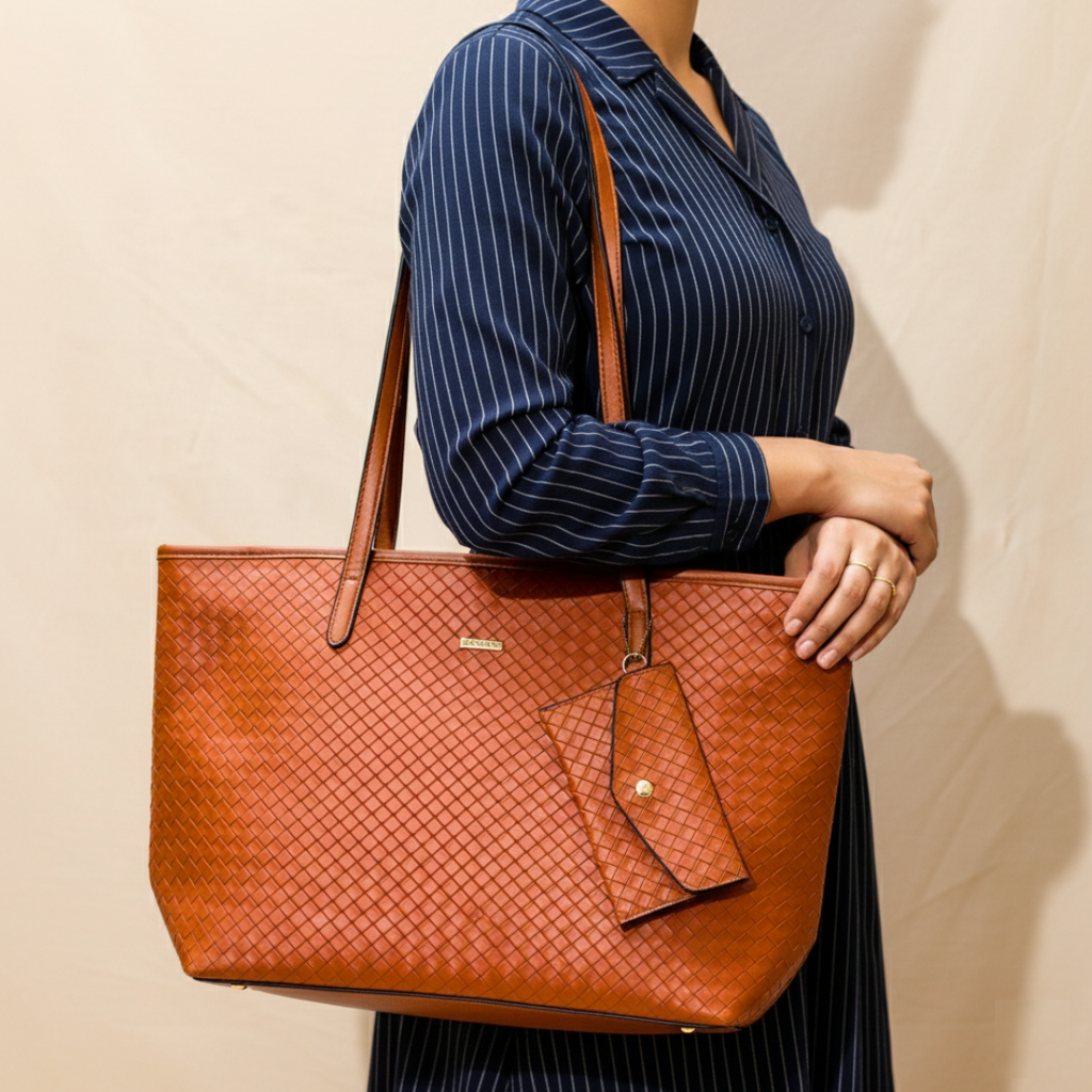 Person holding a brown woven handbag against a beige background