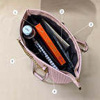 Pink handbag with items including a book, a bottle, and a phone, on a beige background.