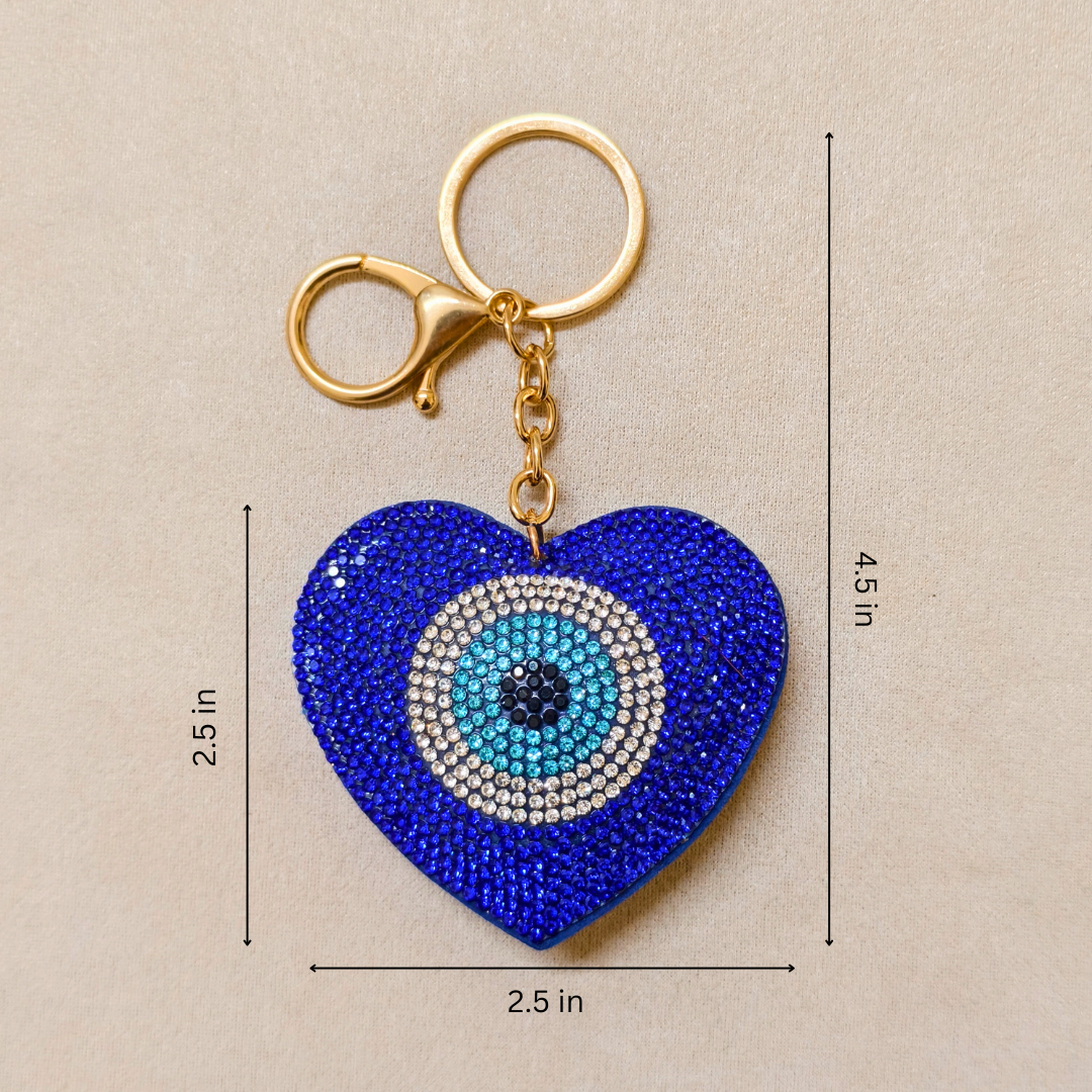 Blue heart-shaped keychain with evil eye design and measurements on a beige background