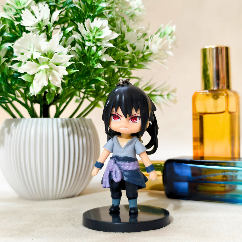 Small figurine with black hair and red eyes next to a vase of white flowers and a bottle.