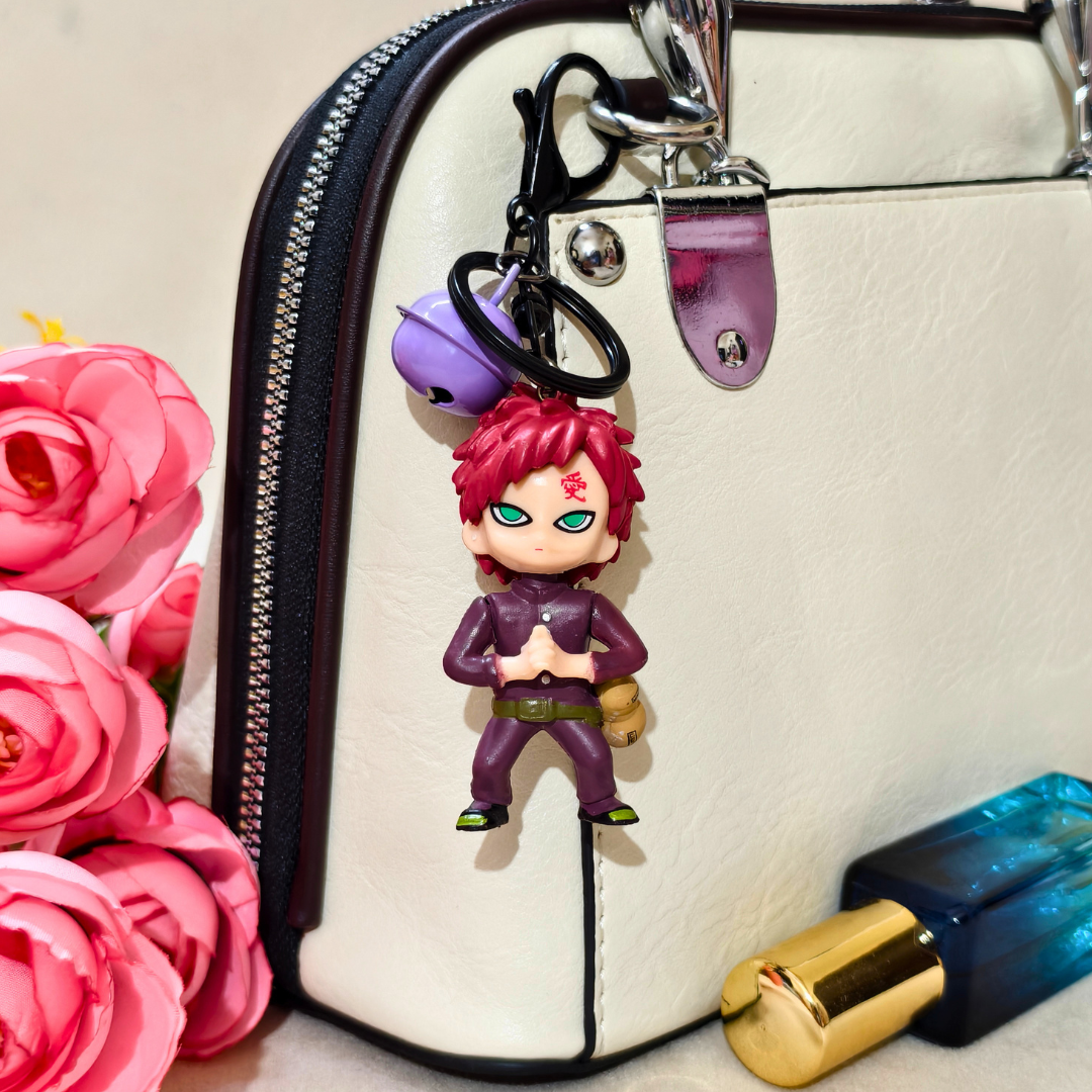 Keychain with a character attached to a handbag next to pink roses and a blue bottle.
