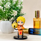 Anime character figurine with a bell, placed on a surface with a plant and bottles in the background.