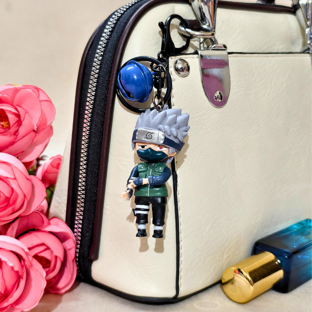 Keychain of a character from a popular anime on a handbag with pink flowers and a lip gloss in the background.
